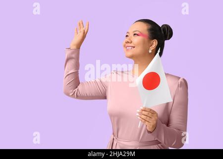 Belle jeune femme asiatique avec drapeau du Japon sur fond de couleur Banque D'Images