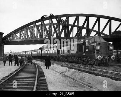 L'équipage de construction vu ici travaille contre la montre pour terminer la pose d'une nouvelle piste double à Dairycoates qui permettra le transfert des voies aériennes.L'achèvement permettra la démolition de la ligne aérienne de 80 ans pour faire place à un nouveau survol de la route qui coûte environ ¿803 000.Notre photo montre: Une British Railways Anglais Electric Type 3 classe 37 Diesel - locomotive électrique transportant un train de voitures de passagers sous le chemin de fer qui doit être démoli.19th février 1962 Banque D'Images