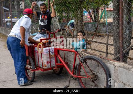 Un élève d'école primaire achète un cornet de crème glacée à un vendeur de chariots à vélo juste à l'extérieur de la clôture de l'école à Jinotega, au Nicaragua Banque D'Images