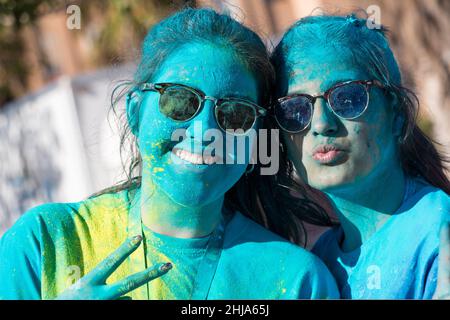 Valencia, Espagne - 27 avril 2019 : gros plan portrait de deux jeunes femmes souriantes avec des lunettes de soleil regardant l'appareil photo recouvert de poudres multicolores pa Banque D'Images