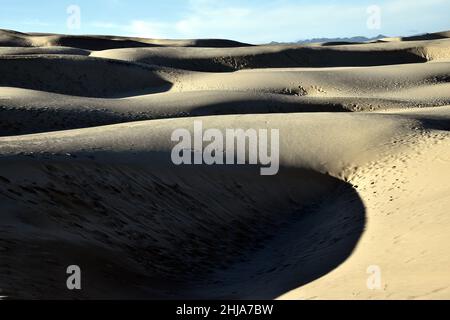 Dunes de sable en lumière et ombre avec empreintes de pas et ciel bleu Banque D'Images