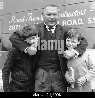 Le tournage de la scène de golf pour 'Goldfinger' au parcours de golf de Stoke Park près de Stoke Poges, Buckinghamshire, étaient Sean Connery ( James Bond ) Gert Frobe ( Goldfinger ) et Harold T Sakata, mieux connu sous le nom de ' Tosh Togo ' dans le monde de Wrestling.Harold joue la partie du caddy pour cette scène.Dans le film James Bond et Goldfinger jouer pour un £5000 pieu.Le jeu est tordu du début à la fin, mais Bond gagne à la fin Bien sûr.Nos Picture shows, Harold T Sakata jouant au combat avec quelques jeunes chasseurs d'autographes 21st mai 1964 Banque D'Images