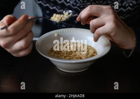 Homme mangeant de la soupe de nouilles.Des hommes qui déjeunent à la maison, goûtant de la soupe au poulet dans un bol.Nourriture à la poubelle.Nouilles instantanées coréennes épicées à l'aide d'une cuillère.Asie rapide f Banque D'Images