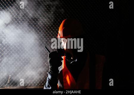 Homme dans un respirateur qui parle sur un talkie-walkie lors d'un incendie dans un bâtiment industriel. Banque D'Images