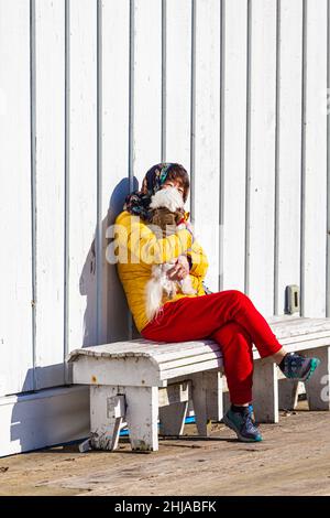 Femme aux couleurs vives avec son chien assis au soleil le long du front de mer de Steveston en Colombie-Britannique, au Canada Banque D'Images