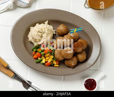 Top vue des boulettes de viande suédoises faites maison avec sauce à la crème, légumes durs, purée de pommes de terre, sauce aux baies de lingonis et persil séché Banque D'Images