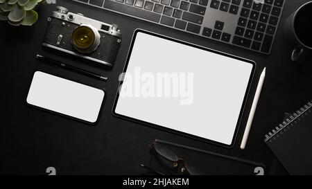 Concept d'espace de travail de bureau, vue de dessus et pose de mélan.Périphériques numériques sur fond de table noir.Maquette d'écran vide pour tablette et smartphone, appareil photo rétro, clavier Banque D'Images