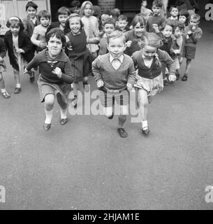 Après une matinée de mathématiques et d'anglais, les élèves de Christopher Hatton Primary ne peuvent pas attendre la pause pour faire un peu d'exercice.15th novembre 1962 Banque D'Images