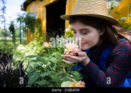 Une vendeuse dans un chapeau de paille arrache une fleur de rose.Garden Shop. Banque D'Images