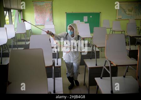 Jakarta, Indonésie.28th janvier 2022.Un membre de la Société indonésienne de la Croix-Rouge procède à la désinfection dans un bâtiment scolaire de Jakarta, en Indonésie, le 28 janvier 2022.L'Indonésie a confirmé jeudi 8 077 nouveaux cas de COVID-19, soit la plus forte augmentation d'un jour depuis le 2 septembre 2021, dans le contexte de la propagation de la variante Omicron dans le pays.Credit: Zulkarnain/Xinhua/Alamy Live News Banque D'Images