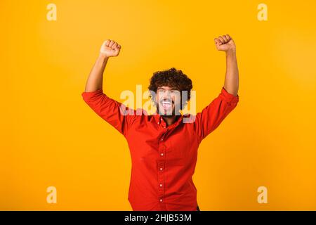 Portrait d'un beau barbu heureux hurlant debout avec un visage excité et se réjouissant de sa victoire.Studio d'intérieur isolé sur fond orange Banque D'Images