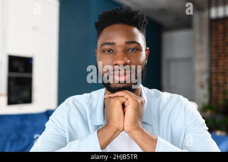 Portrait d'un heureux homme multiracial assis au bureau et regardant la caméra, impliqué dans la réunion vidéo.Webcam pour homme intelligent en chemise bleue Banque D'Images