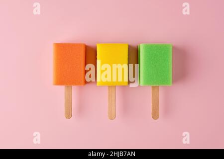 Crèmes glacées à base de popsicle colorées en éponge sur fond rose pastel.Concept minimaliste et créatif d'hygiène domestique. Banque D'Images