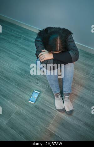 Femme désespérée méconnaissable avec une dépendance au téléphone couvrant son visage Banque D'Images