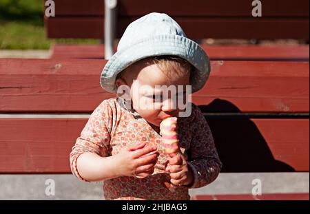 Umea, Norrland Suède - 30 mai 2021 : une petite fille mange de la glace collante par elle-même Banque D'Images