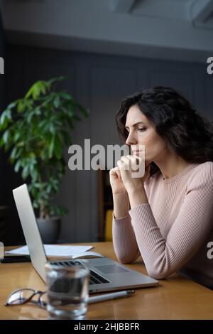 Une jeune femme d'affaires qui regarde l'écran d'un ordinateur portable a contrarié la pensée des employées à propos de la solution Banque D'Images