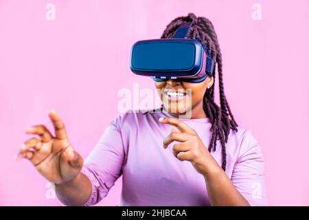 femme ethnique noire regardant la simulation de la vie vidéo en studio sur fond rose Banque D'Images