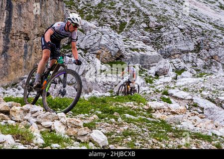 Les participants du Trophée Cortina 2021 descendent sur leurs vélos sur la surface rocheuse de la cabane de montagne Refugio Averau. Banque D'Images