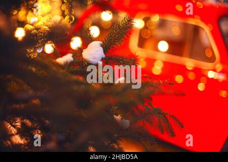 L'esprit des fêtes.Confortable photo de style de Noël avec voiture rétro rouge dans la cour couverte de neige de la maison décorée avec des branches de pin et des lumières de Noël.Sortie Banque D'Images