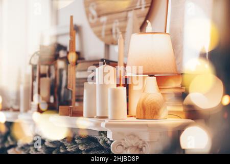 Lampe et de nombreuses bougies sur cheminée mantel dans la maison décorée pour les vacances de Noël, foyer sélectif.Détails chauds dans l'intérieur de la maison.Salle de séjour rustique roo Banque D'Images