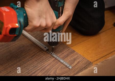 Visser la vis à l'aide d'un tournevis pour coller le détail de la pièce de fer sur le panneau.Assemblage de meubles à la maison.Copier l'espace.En utilisant la construction et Banque D'Images