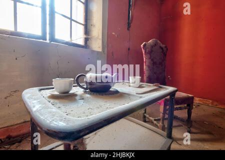 Septembre 2021, Italie.Salle de séjour dans un château abandonné, avec table, chaises et service de thé.Urbex Banque D'Images