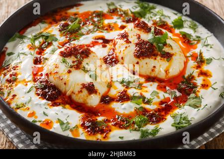 Petit déjeuner turc simple et savoureux le Cilbir est composé d'œufs parfaitement pochés, servis sur un délicieux yaourt au lait et au beurre épicé accompagné de flocons de poivre rouge clos Banque D'Images