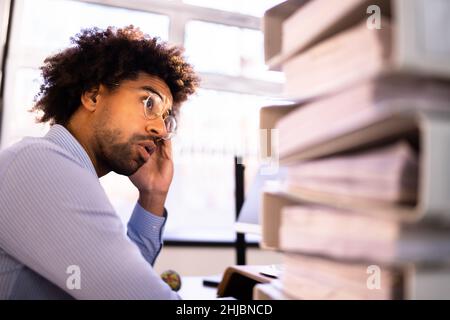 Un jeune homme d'affaires fatigué de calculer l'impôt à la réception au bureau Banque D'Images