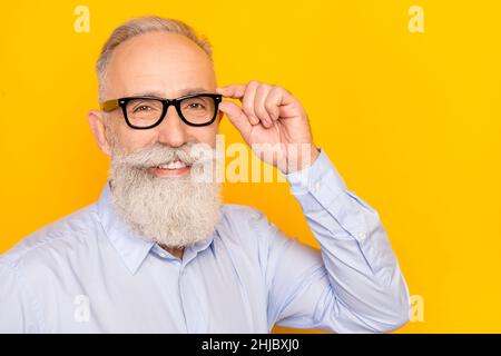 Photo de mignon doux âge gentleman porter chemise bleu bras lunettes foncé espace vide isolé couleur jaune fond Banque D'Images