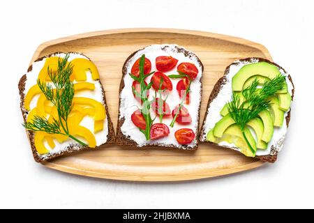 Variété de sandwiches pour le petit déjeuner - tranche de pain noir de grain entier, poivron jaune, fromage à la crème, avocat, tomates cerises,garniture avec aneth Banque D'Images