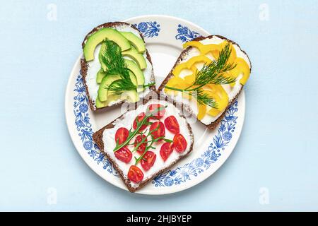 Variété de sandwiches pour le petit déjeuner - tranche de pain noir de grain entier, poivron jaune, fromage à la crème, avocat, tomates cerises,garniture avec aneth Banque D'Images