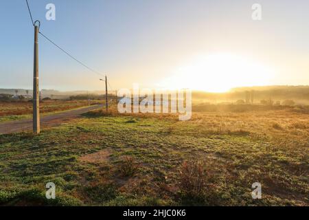 Vue sur le paysage typique de l'Alentejo avec village portugais dans le brouillard du matin un soleil levant au sentier de randonnée de Rota Vicentina près de Carrascalinho, Aljezur Banque D'Images