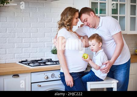 famille avec un petit enfant et une jeune femme enceinte dans la cuisine. Banque D'Images