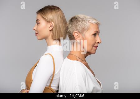 vue latérale d'une jeune femme debout dos à dos mère d'âge moyen isolée sur gris Banque D'Images