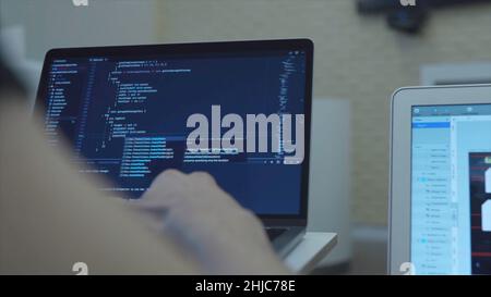 Gros plan des mains du développeur web programmant Javascript, codant HTML sur ordinateur portable.Vue de l'arrière Banque D'Images
