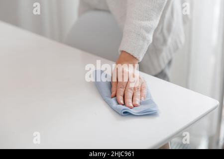 Nettoyage de la table avec un chiffon en microfibre bleu.Désinfectez les surfaces de prévention contre le coronavirus dans les hôpitaux et les espaces publics.Femme main utilisant humide Banque D'Images