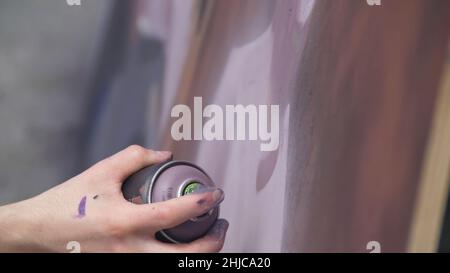 Une main avec un vaporisateur qui dessine un nouveau graffiti sur le mur. Photo de l'élaboration d'un graffiti sur un mur en bois close-up. Le concept de st Banque D'Images