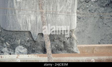 Gros plan du godet de pelle hydraulique chargeant le minerai dans le tombereau à benne basculante.Industrie minière Banque D'Images