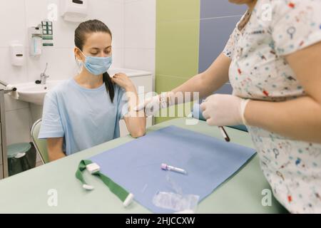 Effectuer un test sanguin sur une veine dans la salle de traitement.L'infirmière pousse une seringue avec une aiguille dans la main du patient.Ecouvillon appuyé contre le Banque D'Images