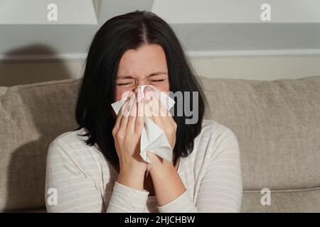 Femme adulte d'âge moyen souffrant de rhinite allergique à la maison.Symptômes de rhume ou d'allergie.Сrying femme pleurant.La femme éternue dans un mouchoir blanc. Banque D'Images