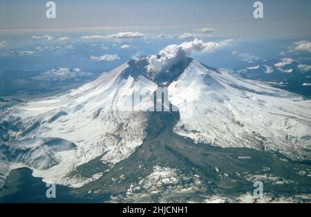 Le mont St. Helens a souvent éclaté entre 1980 et 1986. Une éruption explosive le 19 mars 1982 a envoyé de la pierre ponce et des cendres à 9 miles (14 kilomètres) dans l'air, et a entraîné un lahar (le dépôt sombre sur la neige) qui coulait du cratère dans la vallée de la rivière North Fork Toutle. Une partie du lahar est entrée dans le lac Spirit (coin inférieur gauche), mais la majeure partie du débit est allée vers l'ouest sur la rivière Toutle, atteignant finalement la rivière Cowlitz, à 50 miles (80 kilomètres) en aval. Banque D'Images