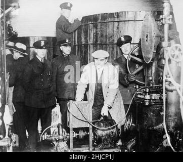 La police de Detroit inspecte l'équipement trouvé dans une brasserie souterraine clandestine pendant l'ère de l'interdiction, vers 1920s. Banque D'Images