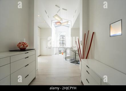 Intérieur moderne du hall dans une maison privée de luxe.Escalier en colimaçon en verre et en métal.Commode blanche. Banque D'Images