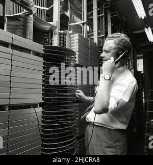 Téléphonie dans le 1970s.Homme dans une pièce avec un tableau de commutation automatique reliant les appels via un dispositif mécanique qui connecte les pièces d'appel et de réception.Le fabricant est LM Ericsson.Suède 1971 Kristoffersson ref. Ed Banque D'Images