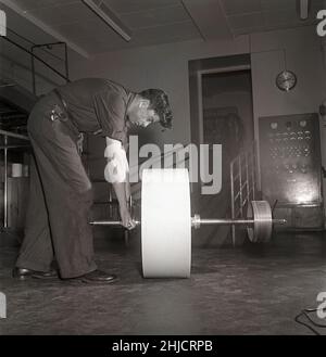 Production de timbres-poste en 1950s.Un homme au timbre suédois printworks du poste suédois manipule le rouleau de papier pour imprimer les timbres-poste.Le papier de Klippes est livré prêt à être collé dans une longueur de 4000 mètres.Suède 1951 Kristoffersson réf. bc44-10 Banque D'Images