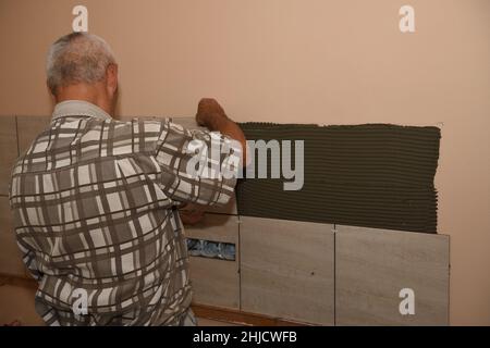 Le maçon place des carreaux sur le mur de la cuisine Banque D'Images