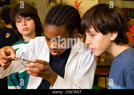 Éducation École primaire ou moyenne classe de sciences de 6 e année extraction d'ADN jeune fille et garçon travaillant sur l'expérience comme un autre étudiant de sexe masculin regarde dessus Banque D'Images