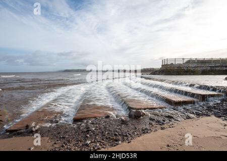 Longue exposition de la cascade de la rivière Avill qui coule sur la plage de Dunster dans le Somerset Banque D'Images