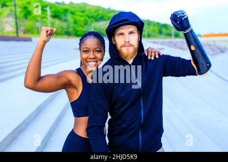 jeune couple de course mixte souriant dans les vêtements de sport se réchauffant en plein air en arrière-plan de sity tôt le matin Banque D'Images