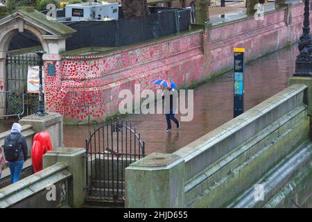 Un piéton muni d'un parapluie drapeau de l'Union passe devant les cœurs rouges sur le mur commémoratif national Covid, dans le centre de Londres. Banque D'Images